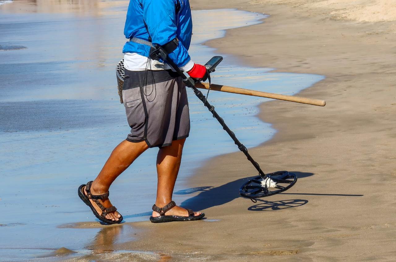 man metal detecting on a beach
