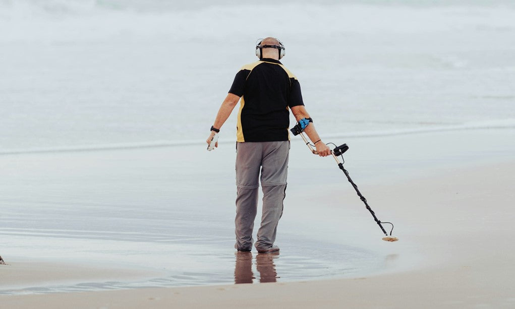 metal detectorist on a beach